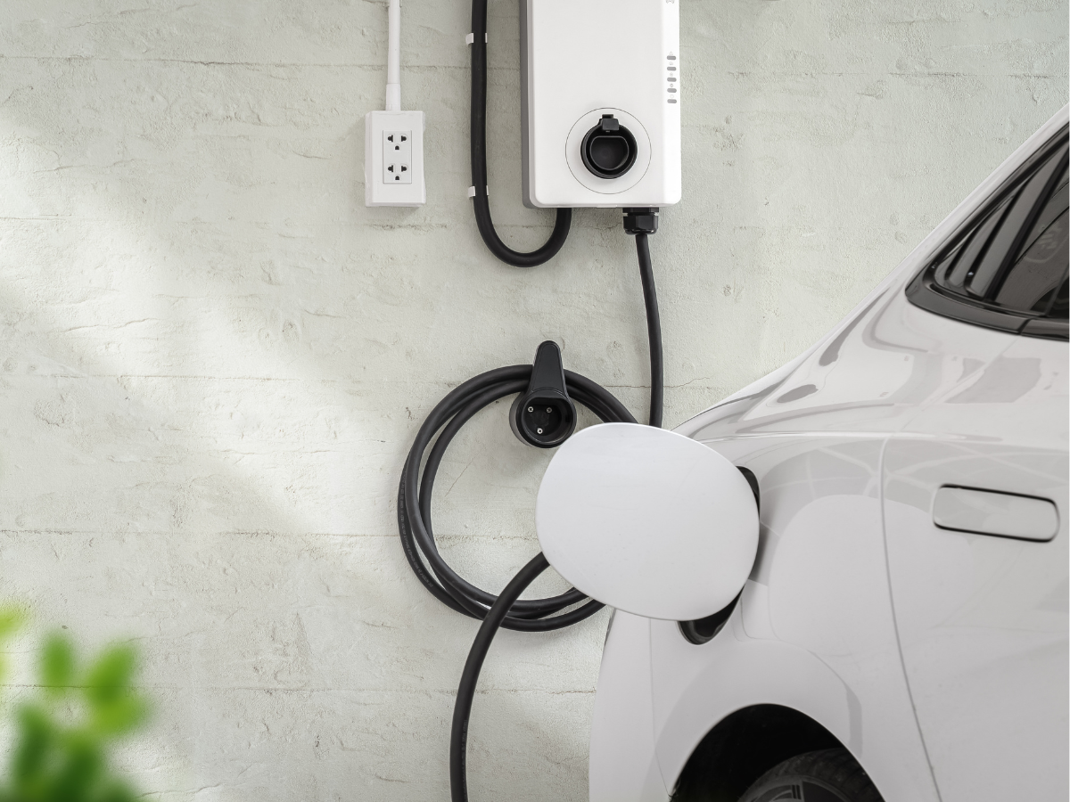 Electric vehicle plugged into a home EV charger installed in a residential driveway